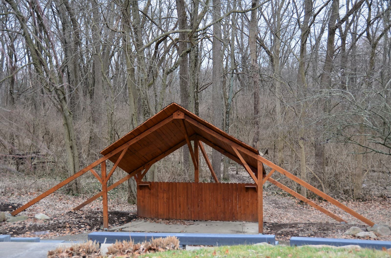 Enkel träcarport med spetsigt tak vid en skogsbacke
