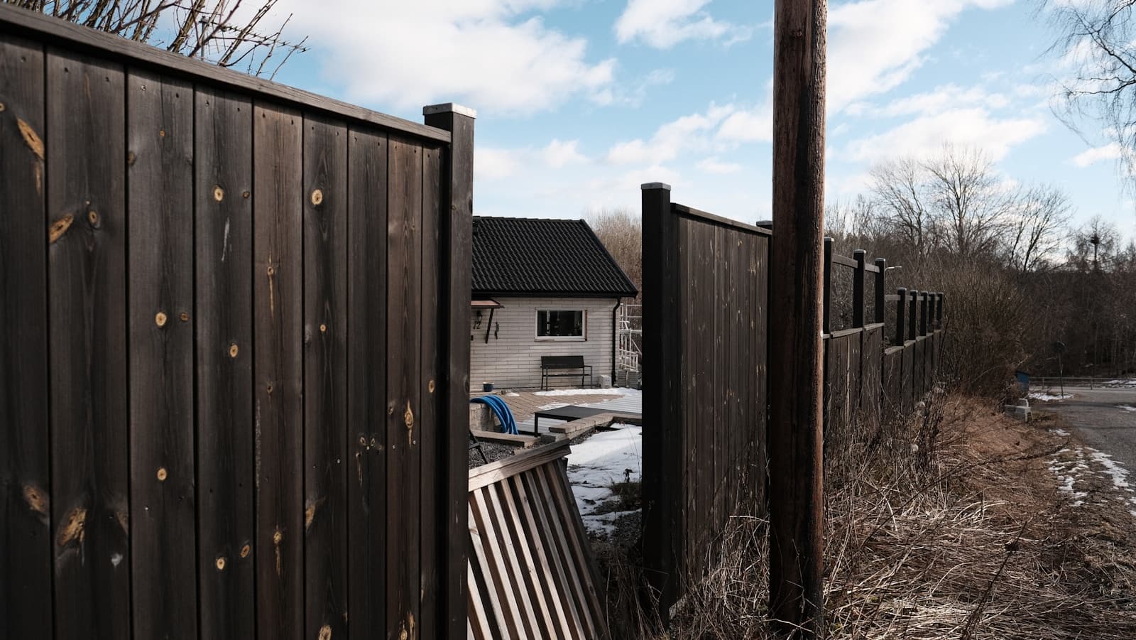 Mörkt målat trästaket framför ett bostadshus